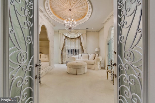 sitting room with a raised ceiling, crown molding, carpet flooring, and a notable chandelier