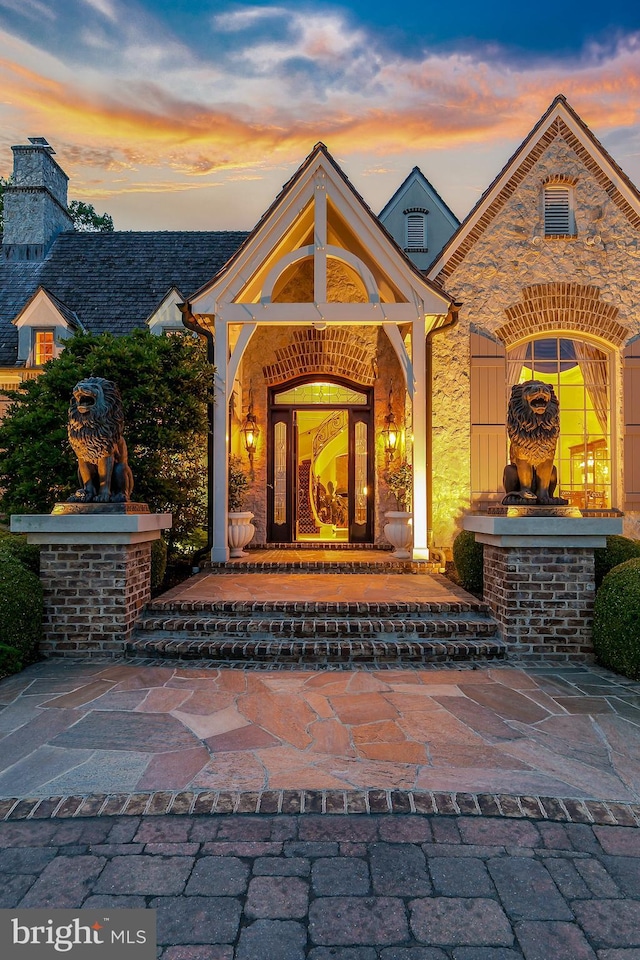 exterior entry at dusk featuring a fireplace