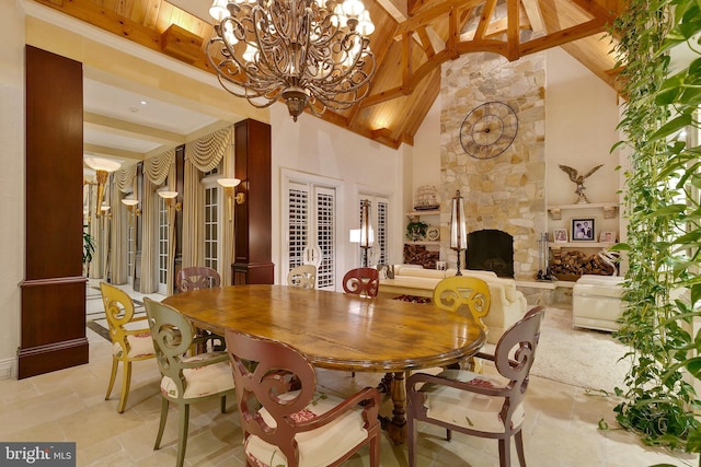 dining room with beamed ceiling, a stone fireplace, a chandelier, and high vaulted ceiling