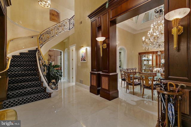 entrance foyer featuring ornamental molding, a towering ceiling, and an inviting chandelier