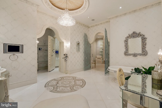 bathroom with tile patterned flooring, vanity, a notable chandelier, ornamental molding, and a bathing tub