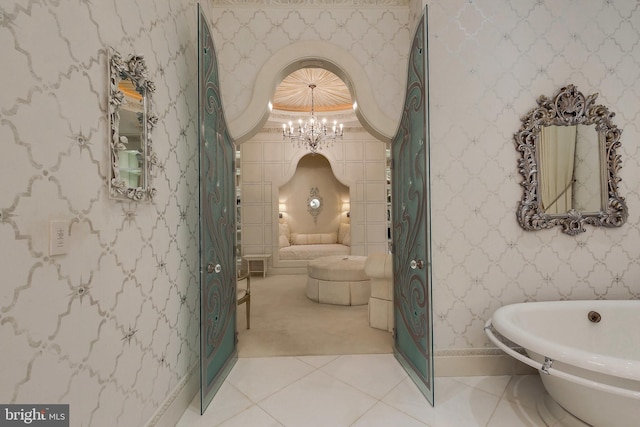 bathroom featuring tile patterned flooring, a bathing tub, and a chandelier