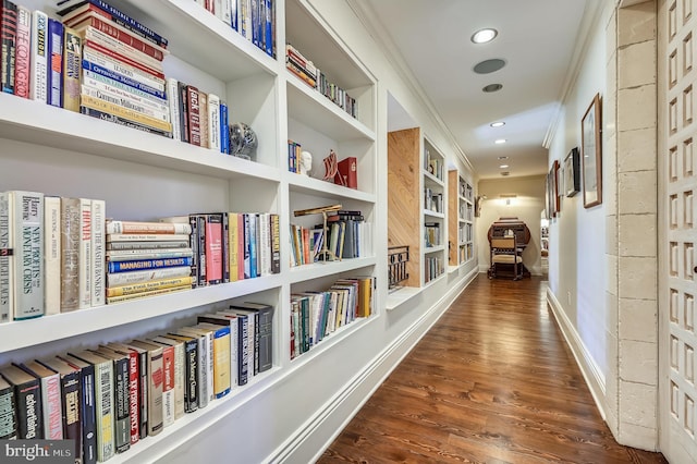 hall with crown molding, dark wood-type flooring, and built in shelves