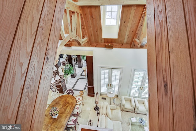 carpeted living room with wood walls, beam ceiling, a skylight, and a high ceiling