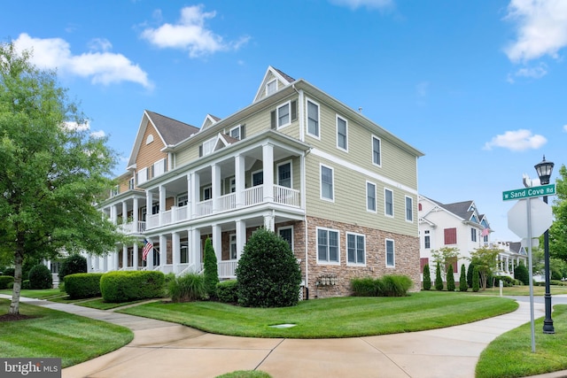 view of front of home with a balcony and a front yard