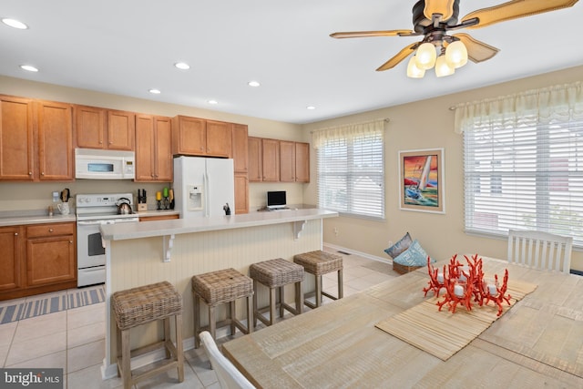 kitchen featuring a kitchen island, plenty of natural light, a breakfast bar area, and white appliances