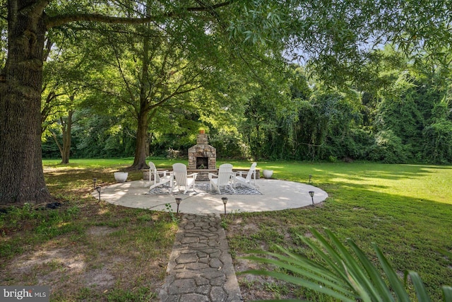 view of yard featuring an outdoor stone fireplace and a patio area