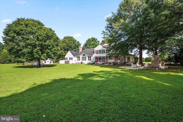 view of yard featuring an outdoor fireplace and a patio