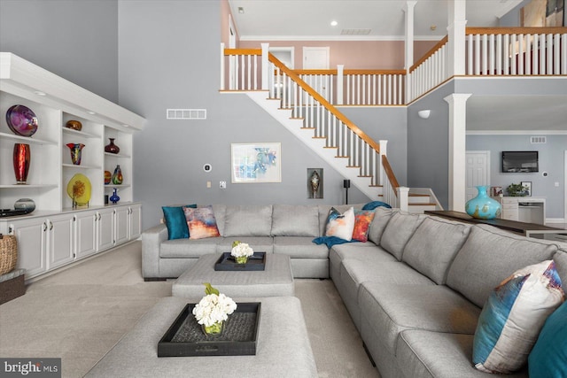 living room featuring ornamental molding, decorative columns, light carpet, and a high ceiling