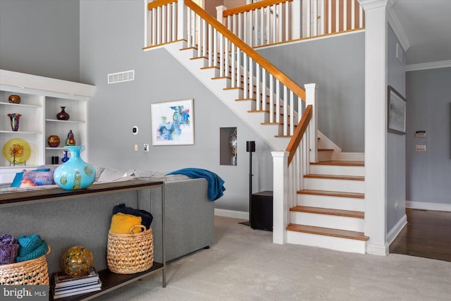 staircase with crown molding, carpet, and a high ceiling