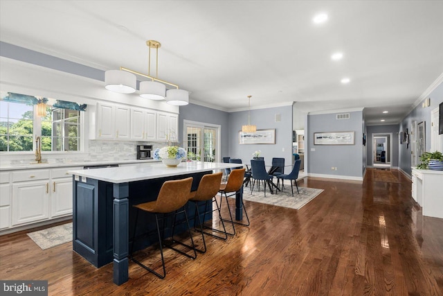 kitchen with white cabinetry, pendant lighting, a center island, and sink