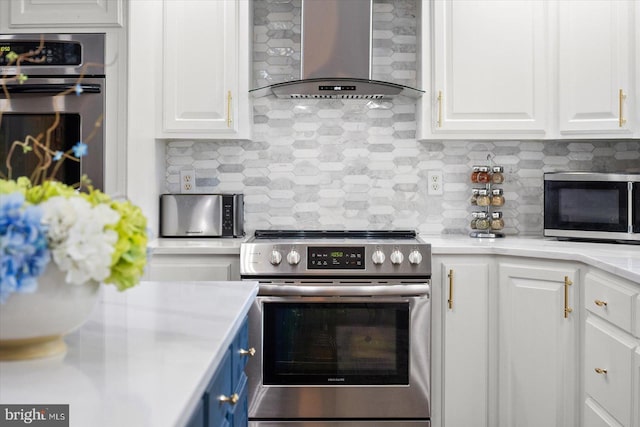 kitchen featuring white cabinetry, wall chimney range hood, backsplash, and stainless steel appliances