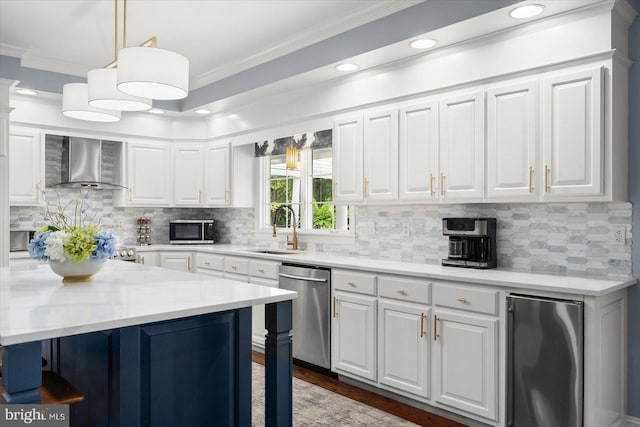 kitchen featuring sink, appliances with stainless steel finishes, white cabinets, decorative light fixtures, and wall chimney exhaust hood