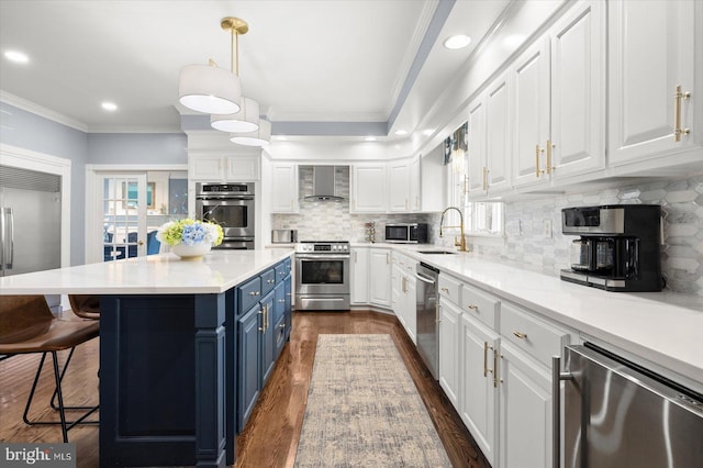 kitchen featuring blue cabinets, white cabinetry, appliances with stainless steel finishes, and wall chimney exhaust hood