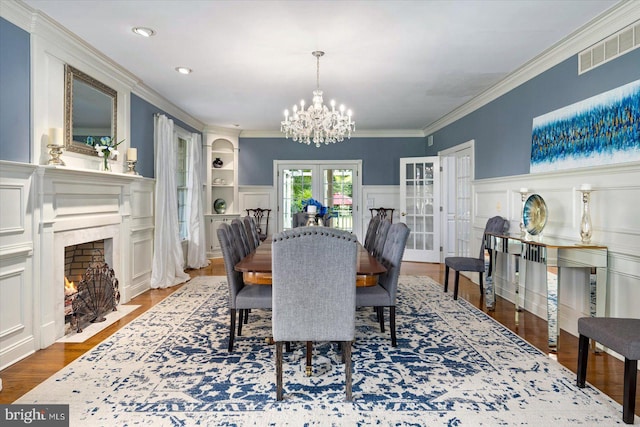 dining room with ornamental molding, dark wood-type flooring, an inviting chandelier, and french doors