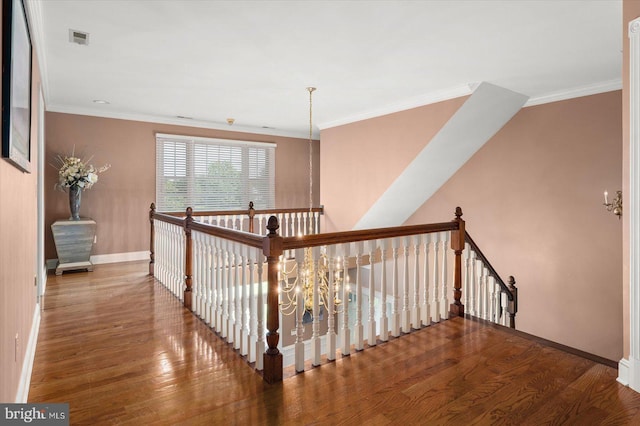 stairway featuring hardwood / wood-style floors, crown molding, and a chandelier