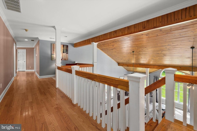 hall featuring crown molding, light hardwood / wood-style flooring, and ornate columns