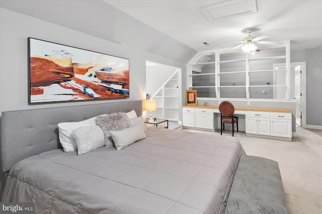 carpeted bedroom featuring lofted ceiling and built in desk