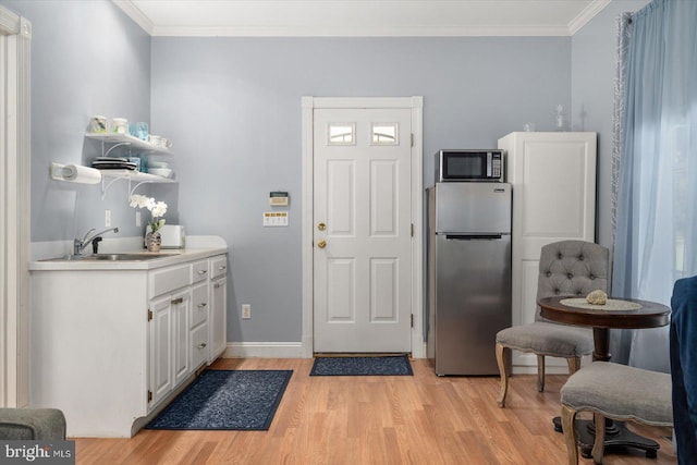 interior space featuring stainless steel appliances, crown molding, white cabinets, and light wood-type flooring