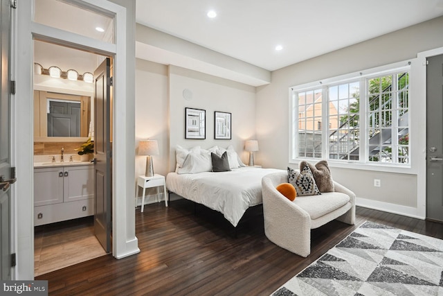 bedroom featuring dark hardwood / wood-style flooring, connected bathroom, and sink