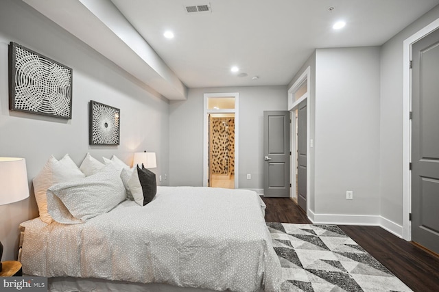 bedroom with ensuite bathroom and dark hardwood / wood-style flooring