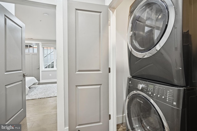 washroom with stacked washer / dryer and wood-type flooring