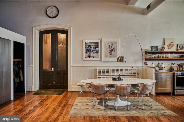 dining room featuring breakfast area, wainscoting, dark wood finished floors, and radiator