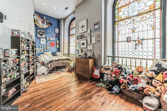 bedroom featuring arched walkways, wood finished floors, and visible vents