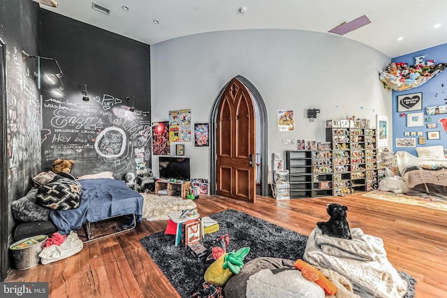 bedroom featuring lofted ceiling, wood-type flooring, visible vents, and arched walkways