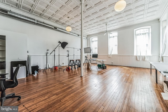 workout room featuring a healthy amount of sunlight, an ornate ceiling, hardwood / wood-style floors, and wainscoting