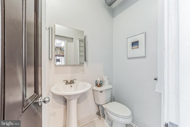 half bathroom with tile patterned flooring, baseboards, and toilet