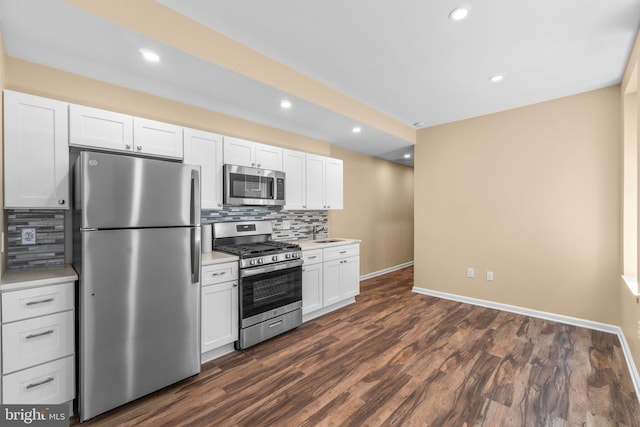 kitchen with appliances with stainless steel finishes, dark wood-type flooring, backsplash, and white cabinetry