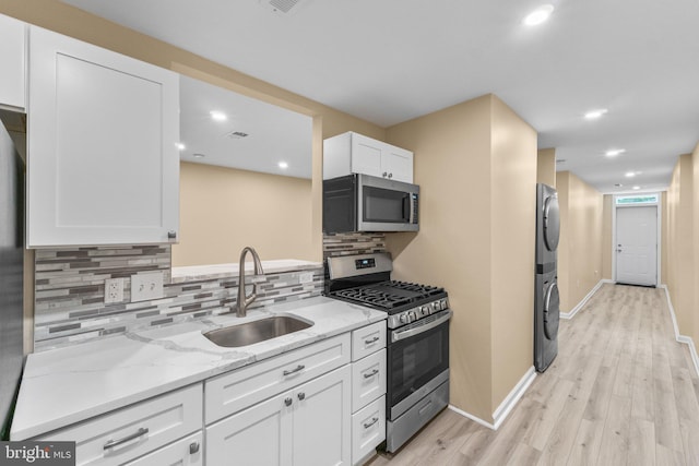 kitchen with white cabinetry, light wood-type flooring, light stone countertops, appliances with stainless steel finishes, and sink