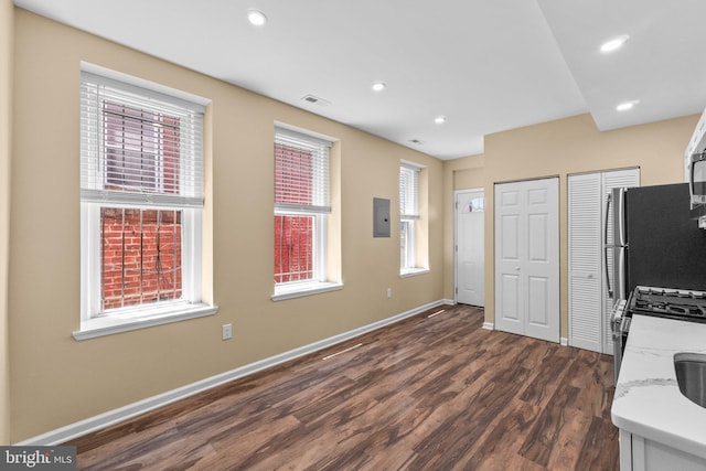 kitchen featuring light stone counters, dark hardwood / wood-style floors, stainless steel appliances, and electric panel