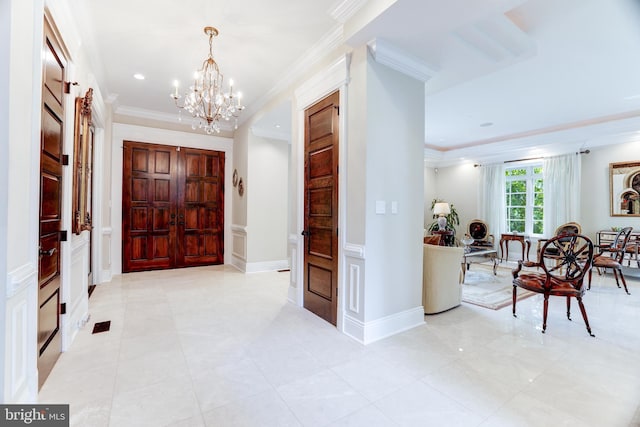 entryway with crown molding and an inviting chandelier