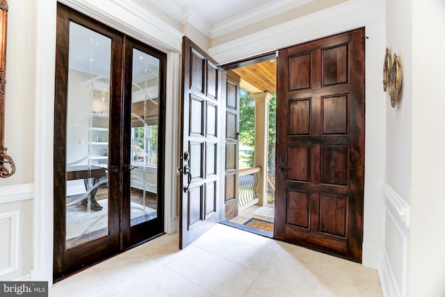 foyer entrance with crown molding, plenty of natural light, light tile patterned flooring, and french doors