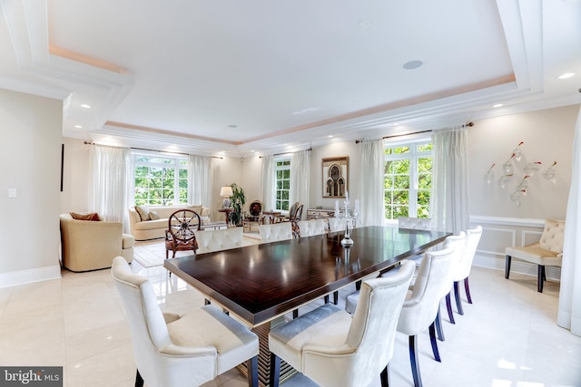 dining room featuring crown molding, light tile patterned flooring, and a tray ceiling