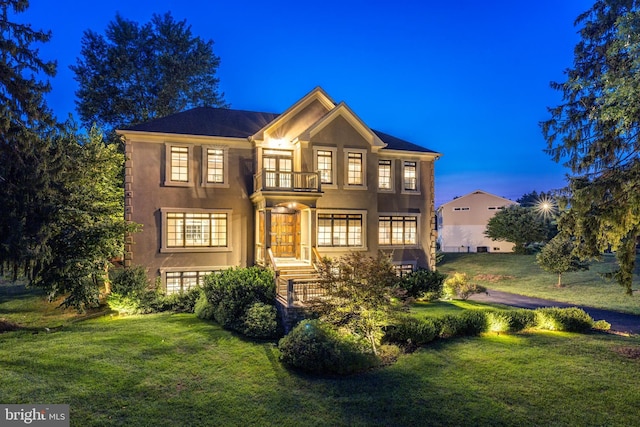 view of front facade featuring a balcony and a lawn