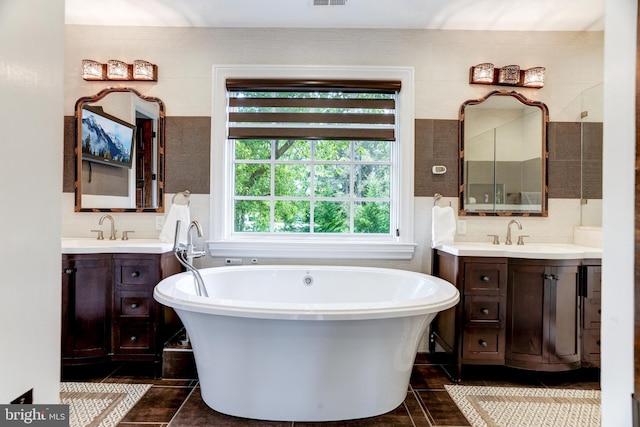 bathroom featuring vanity, a tub to relax in, tile patterned floors, and tile walls