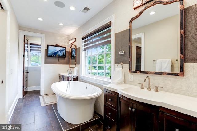 bathroom with tile patterned flooring, vanity, a bathing tub, and a healthy amount of sunlight