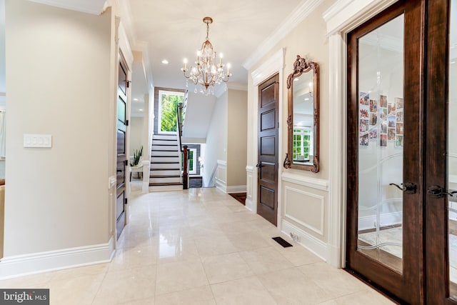 interior space with french doors, ornamental molding, and a notable chandelier