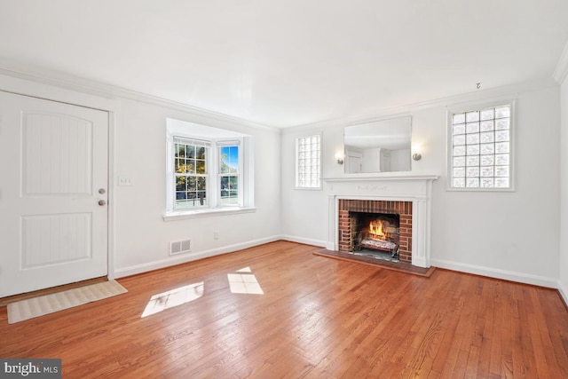 unfurnished living room with crown molding, a brick fireplace, and a healthy amount of sunlight