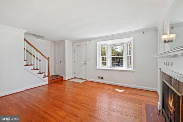 unfurnished living room with hardwood / wood-style flooring and crown molding