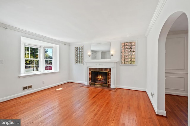 unfurnished living room featuring light hardwood / wood-style flooring, a fireplace, and ornamental molding