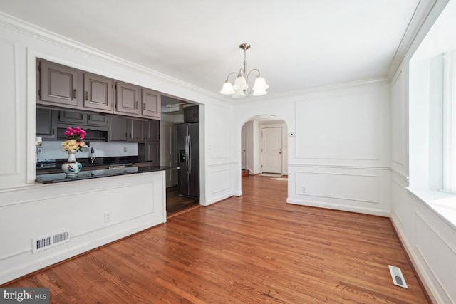 kitchen with sink, wood-type flooring, ornamental molding, stainless steel fridge with ice dispenser, and a chandelier