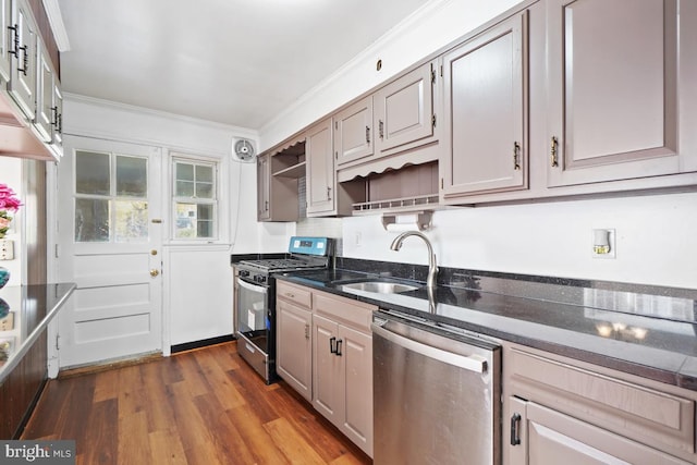 kitchen featuring sink, dark stone countertops, ornamental molding, appliances with stainless steel finishes, and dark hardwood / wood-style flooring