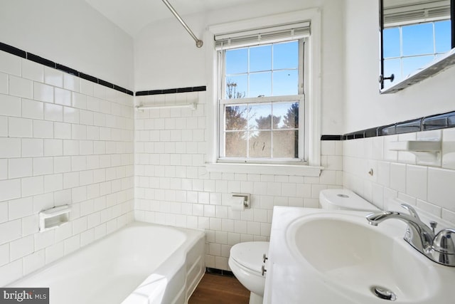 full bathroom featuring sink, tile walls, washtub / shower combination, and toilet