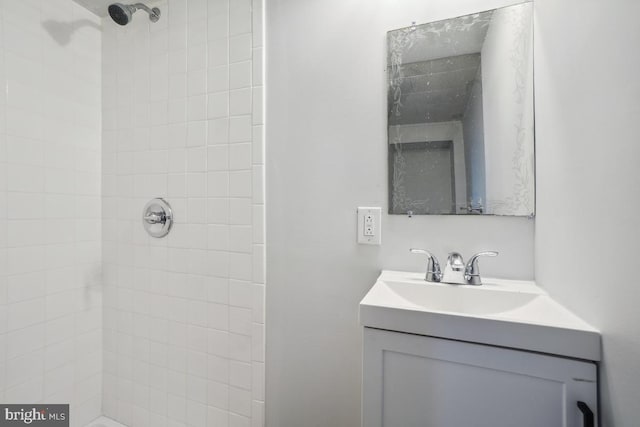 bathroom with a tile shower and vanity