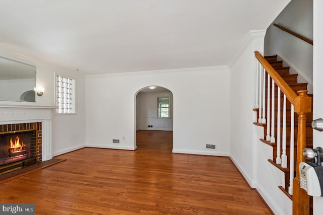 unfurnished living room featuring hardwood / wood-style flooring, ornamental molding, and a fireplace