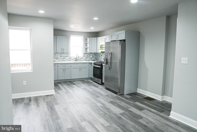 kitchen with gray cabinets, stainless steel appliances, hardwood / wood-style floors, and a wealth of natural light